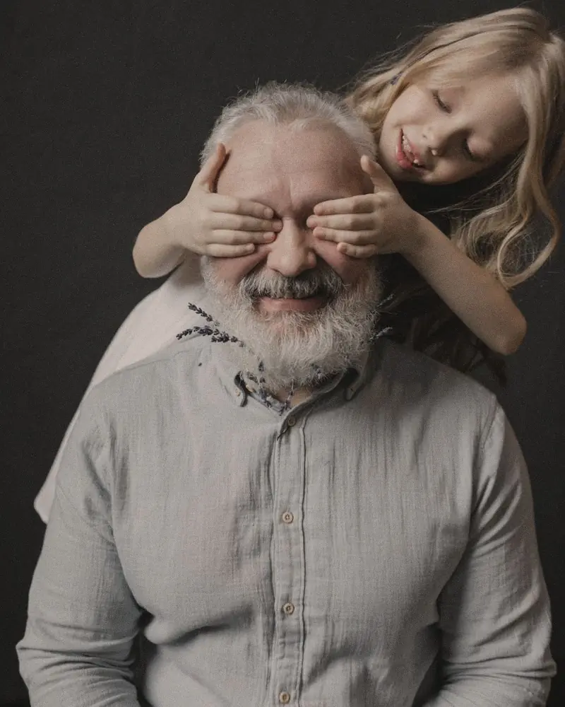 Une petite fille cache les yeux de son grand-père pour lui faire une surprise